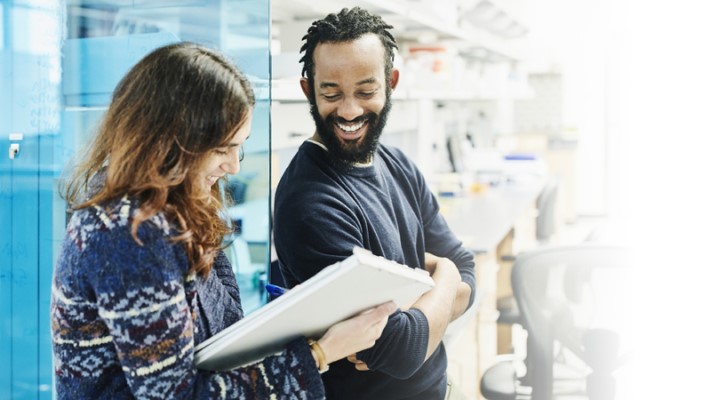 Homme et femme collaborant devant un grand tableau de papier