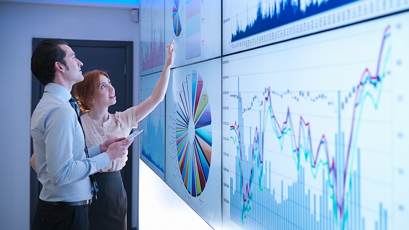 Business colleagues discussing graphs on screen in meeting room