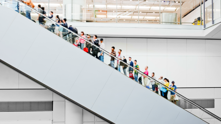 shoppers on escalator in busy mall