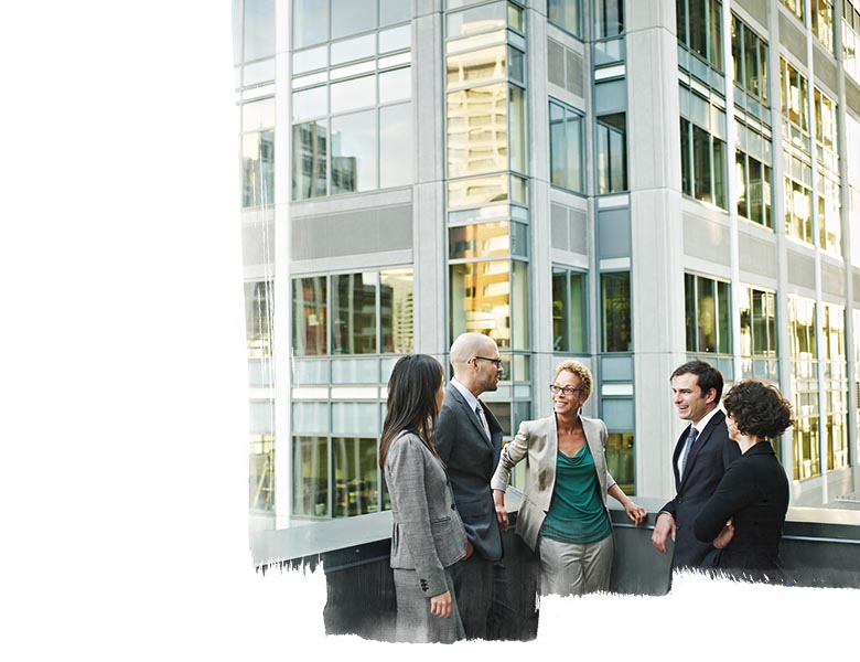 Group of coworkers standing in discussion on deck of office buildings in background