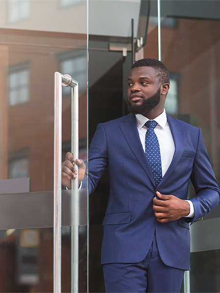 Handsome confident businessman in formal suit walking out of modern office center