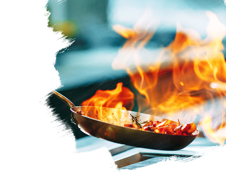 Cooks prepare meals on the stove in the kitchen of the restaurant