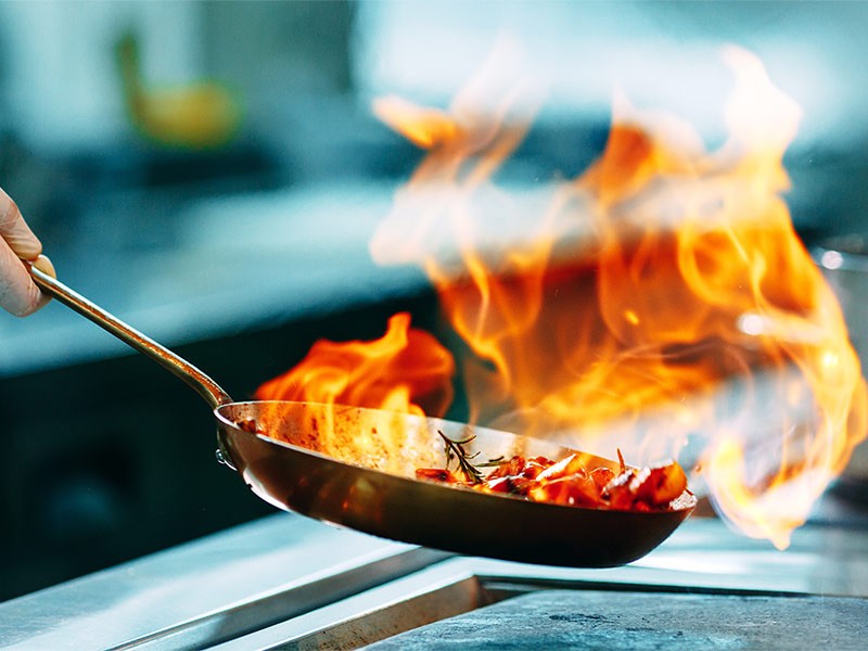 Cooks prepare meals on the stove in the kitchen of the restaurant