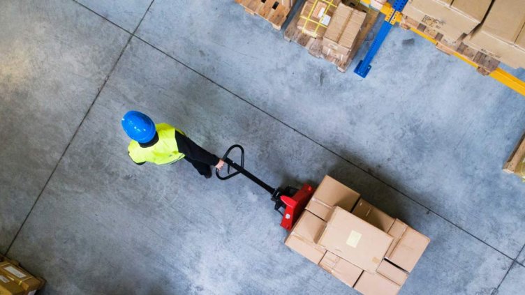 Logistic worker pulling the carton boxes in the warehouse