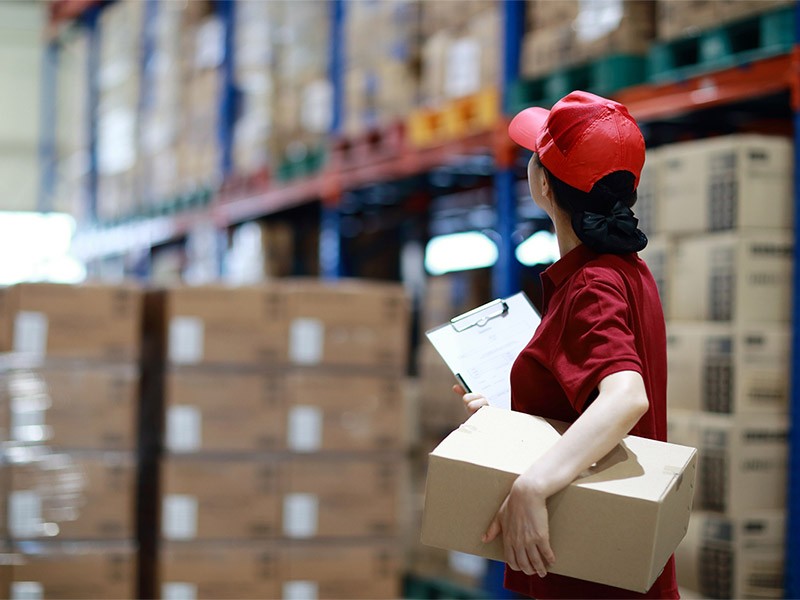 one of the female logistic employee counting the boxes kept in warehouse