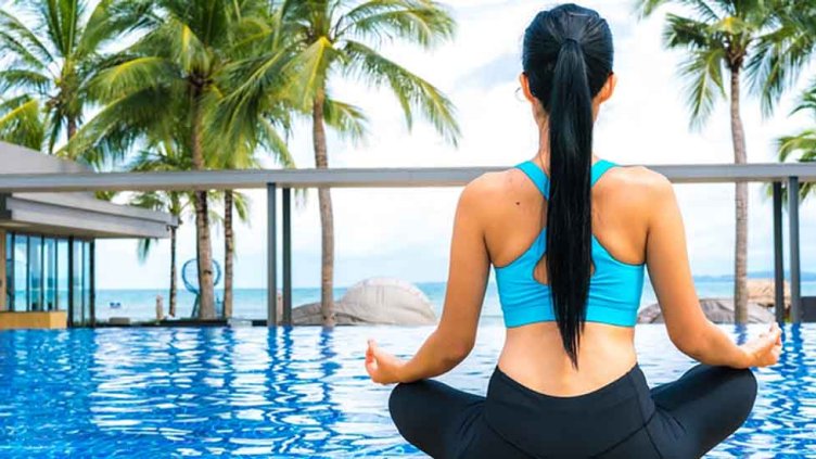 A woman doing Yoga in front of swimming pool