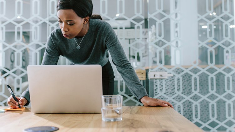 Young woman making notes while working on laptop in office boardroom.Shutterstock ID 1143539495; 