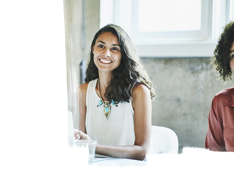 Smiling businesswoman in discussion with colleagues during meeting in office conference room