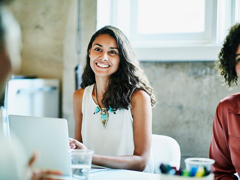 Smiling businesswoman in discussion with colleagues during meeting in office conference room
