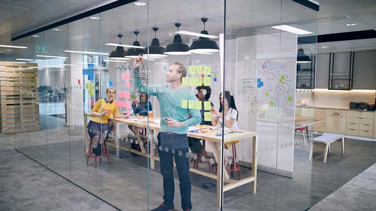 A person is explaining something to the team while writing on a board