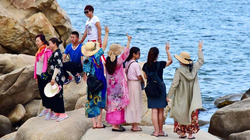 Chinese tourists enjoying the sea side view 