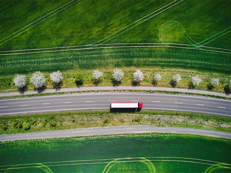 Drone shot direct above a truck moves along a single road.