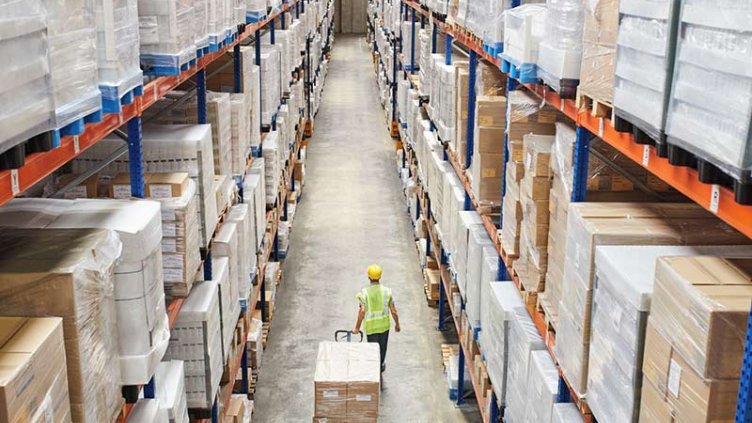 A man taking boxes via trolley in industrial warehouse