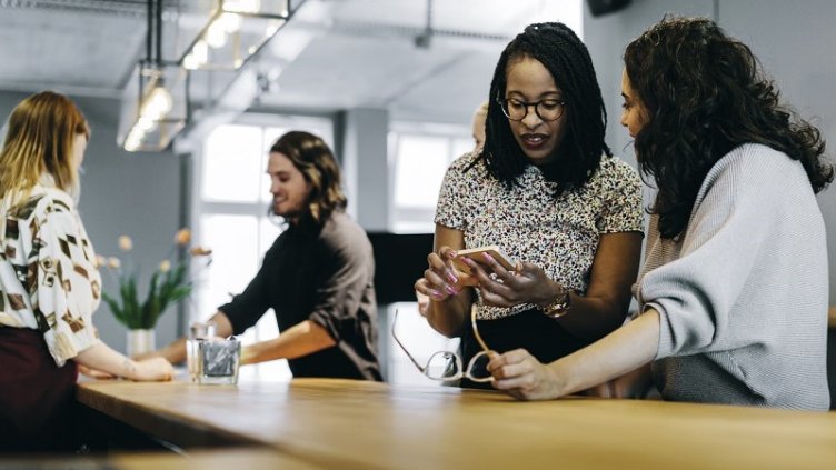 women standing and talking to each at workplace - shows women outrank men