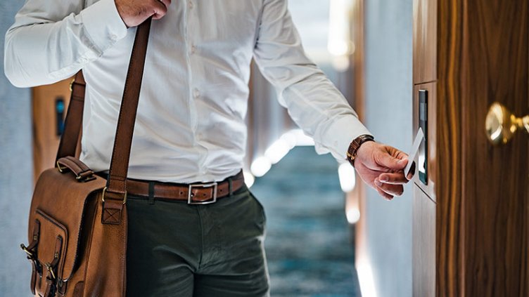 Elegant man unlocking hotel room door with key card.