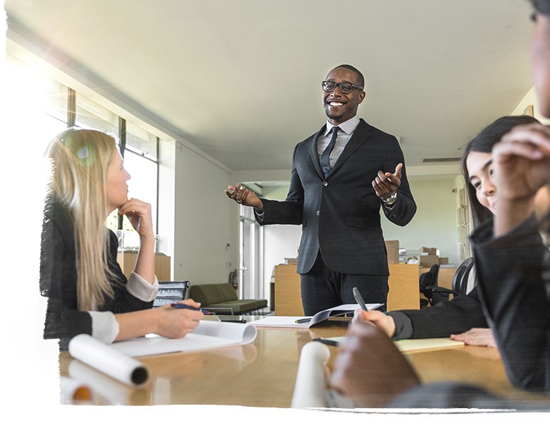 Image of a smiling man leading a meeting of diverse coworkers in an office