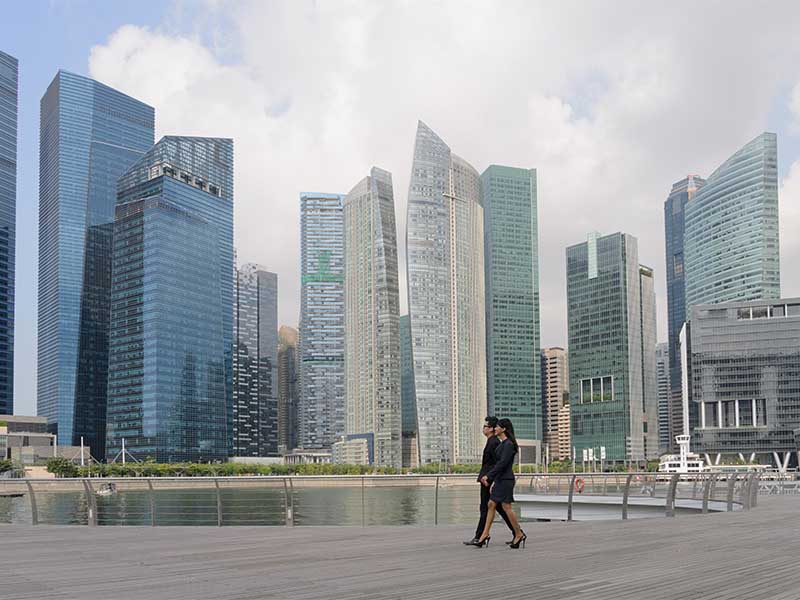 Two employees having conversation while walking beside the real estate buildings in a smart city