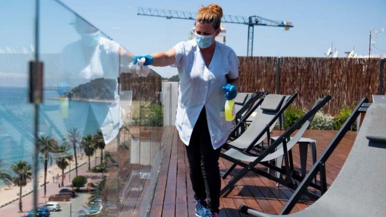 cleaning staff disinfectanting the hotel glass wall during covid