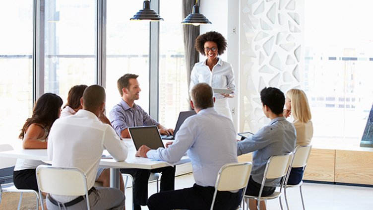 team members listen to businesswoman giving meeting