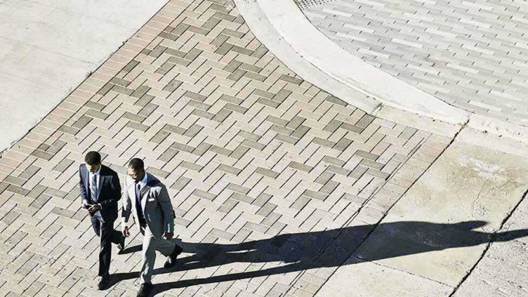 Overhead view of two investors walking while discussing