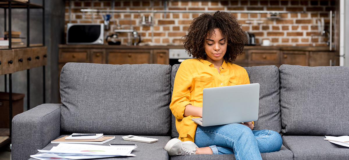 woman sits on couch while remote working