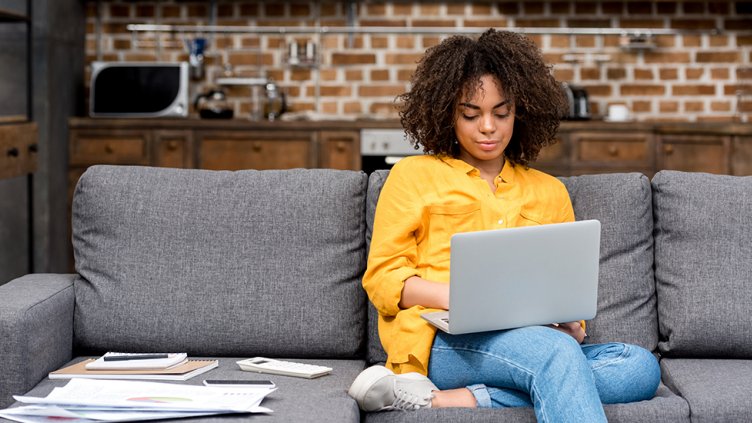 woman sits on couch while remote working