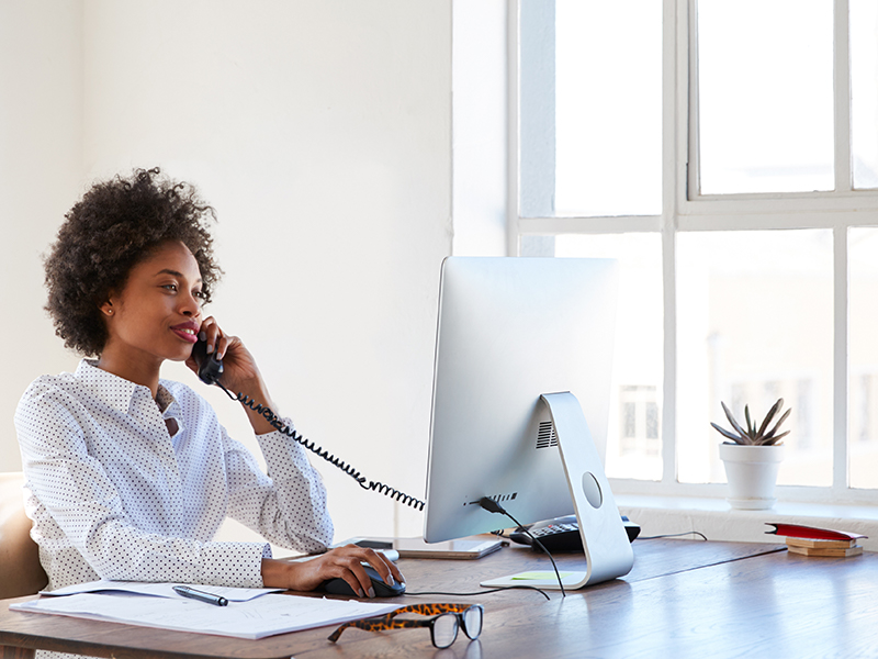 young woman on the phone in front of desktop computer