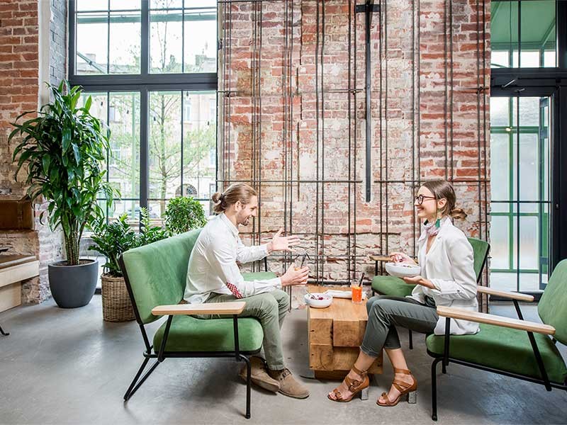 Two colleagues speaking in a casual worskpace meeting area