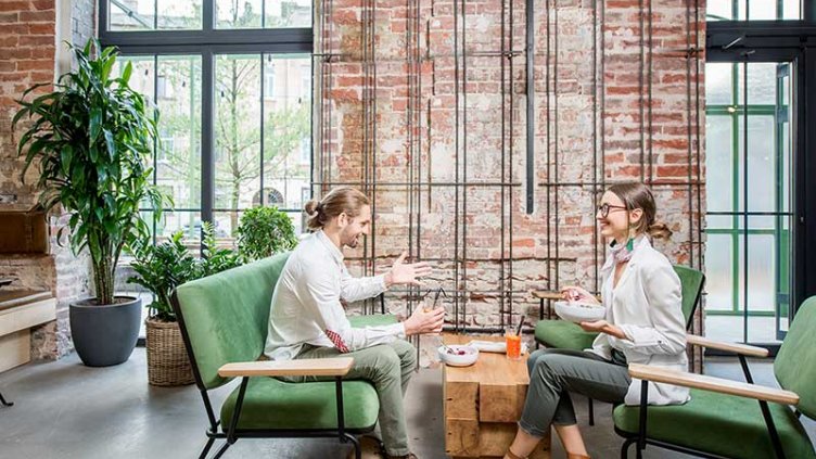 Two colleagues speaking in a casual worskpace meeting area