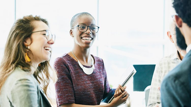 Two women standing at work talking to male colleagues