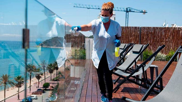 Hotel staff worker wearing mask and cleaning the glass pane