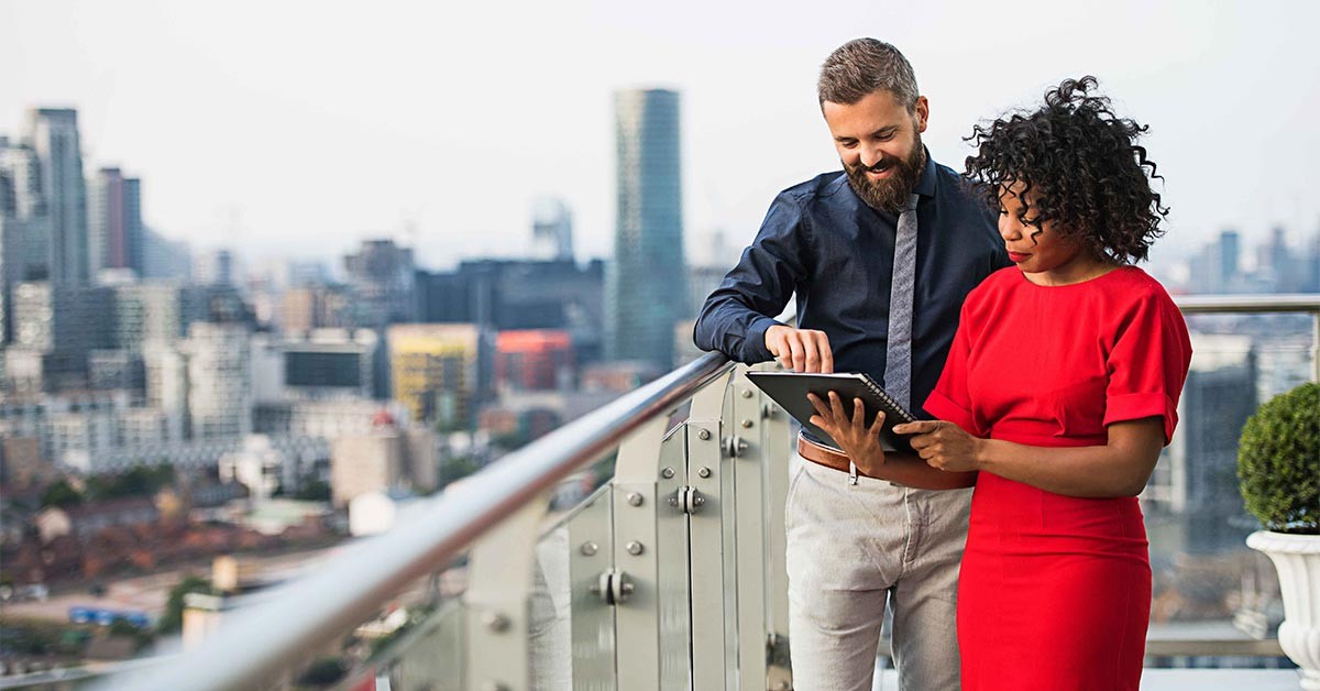 A portrait of two businesspeople standing against London view panorama.