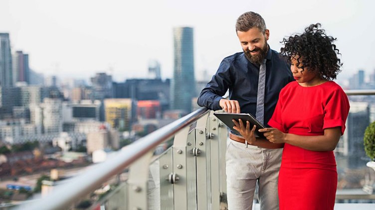 A portrait of two businesspeople standing against London view panorama.