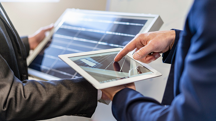 Close-up of two businessmen in office with solar cell and tablet