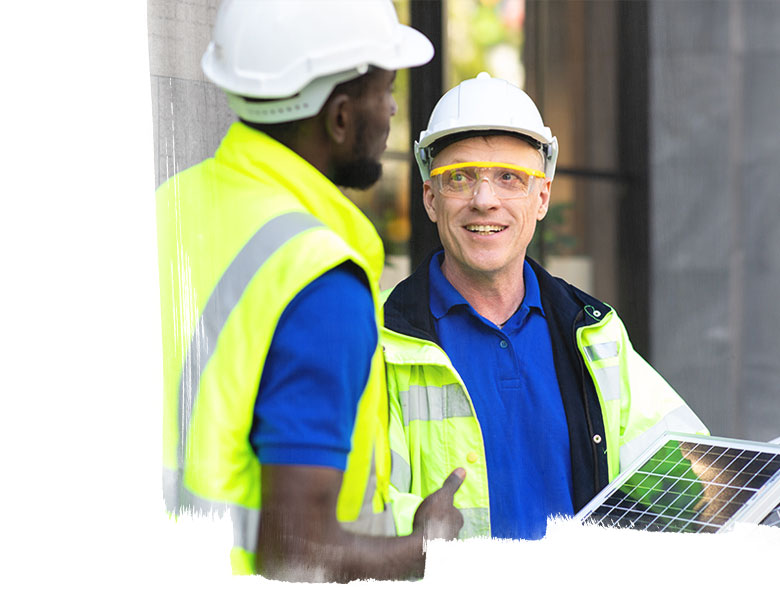 Two engineers African american engineer and caucasian electrician wearing white hard hat walk in new building holding solar panel on hand and Discuss Work