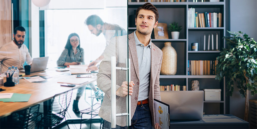 Man closing a door as he is about to enter a meeting with three coworkers