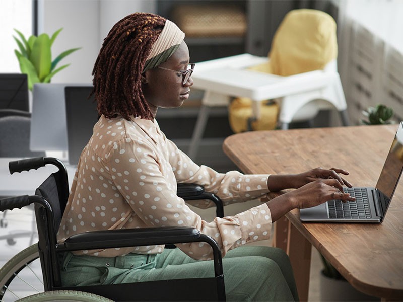 A female employee sitting at wheelchair and working on her laptop