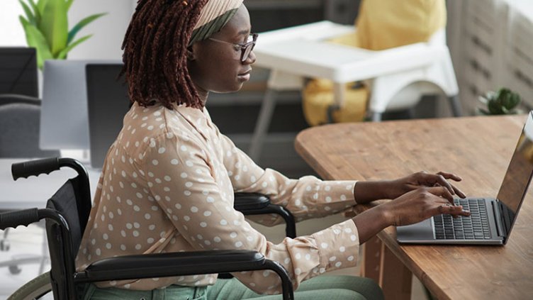 A female employee sitting at wheelchair and working on her laptop