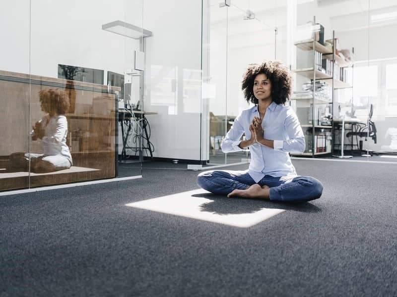 Woman attending wellness program and practicing yoga in the office workplace