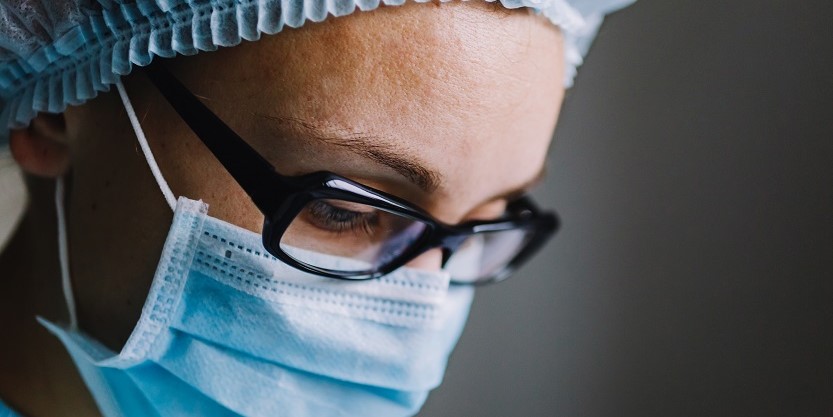 A lady doctor wearing a surgical cap and mask